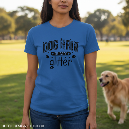 Person wearing a blue t-shirt with 'Dog Hair is My Glitter' text, standing in a park with a dog.