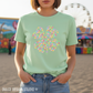 Woman wearing light green Bella Canvas tee with colorful heart design